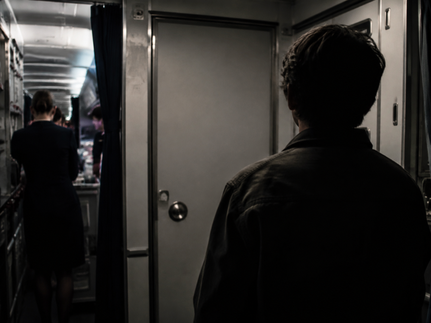 Anonymous figure near a cockpit door illustrating the third-party hijacking scenario in MH370